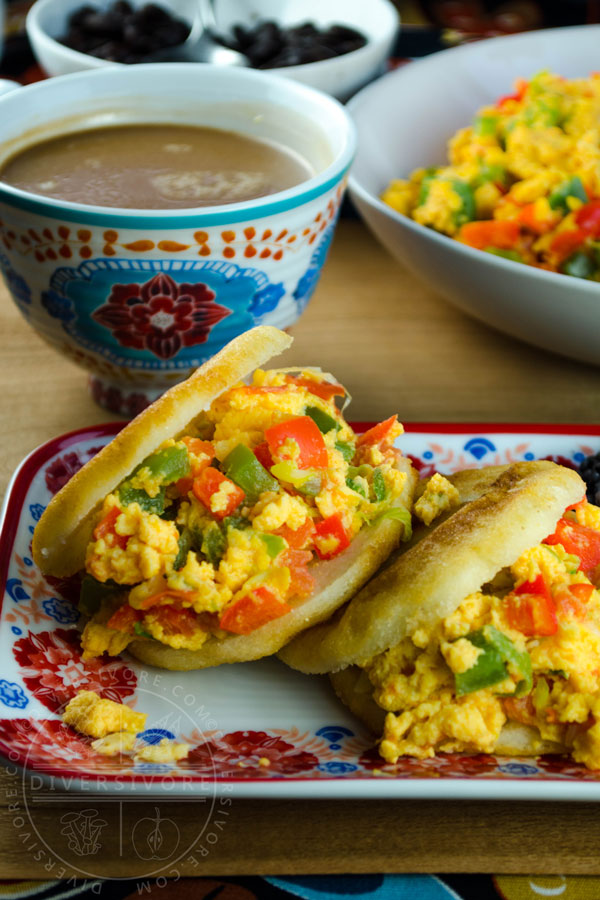 Perico served in arepas with black beans on a colourful rectangular plate