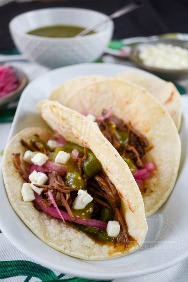 Tacos with Instant Pot Brisket with Pasilla-Morita Adobo, served with salsa verde, pickled onions, and queso fresco