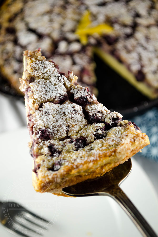 A slice of saskatoon berry clafoutis being lifted from a pan with a cake server