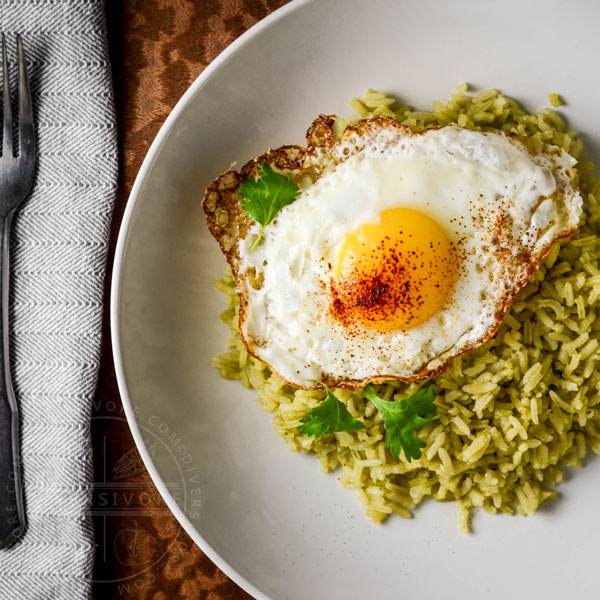 Green Rice (Arroz Verde) on a large white plate, topped with a fried egg dusted with ancho chili powder.