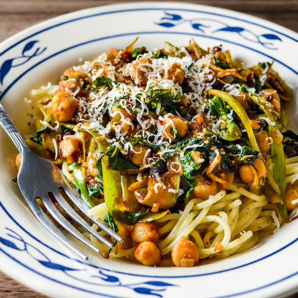 Chickpea and Gai Lan Spaghettini in a blue and white bowl with a fork