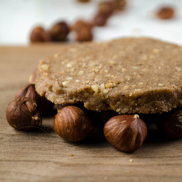 Chocolate Hazelnut Shortbread cookie resting on hazelnuts on a wood backdrop