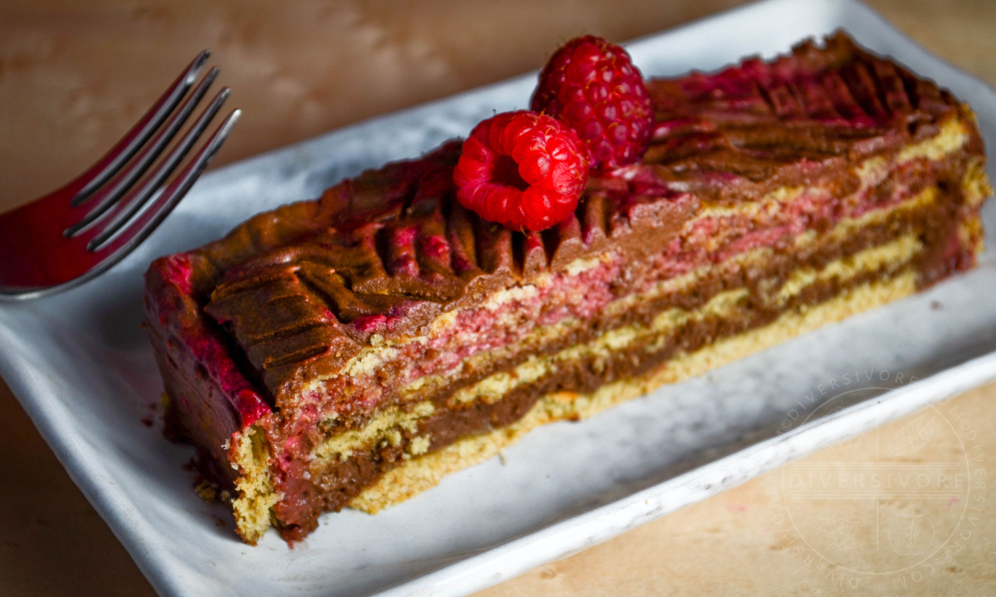 Chocolate Raspberry Rose Icebox Cake slice topped with two raspberries and served on a rectangular plate