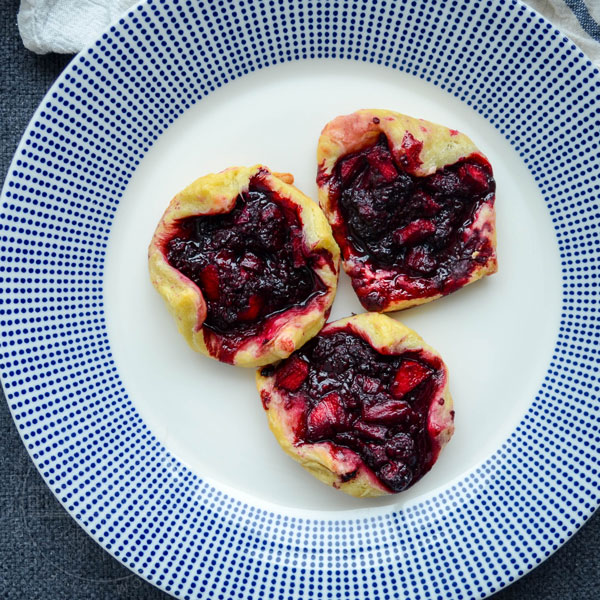 Dewberry and apple puff pastry tarts on a white plate with blue dots