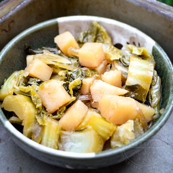 Simmered cauliflower leaves and potatoes in a dashi stock, served in a small green and white Japanese bowl