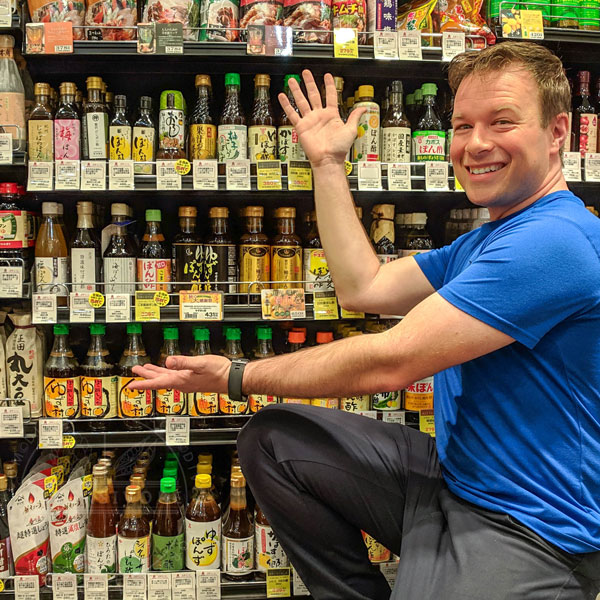 The author posing in front of a wall of ponzu sauce varieties in a store in Tokyo