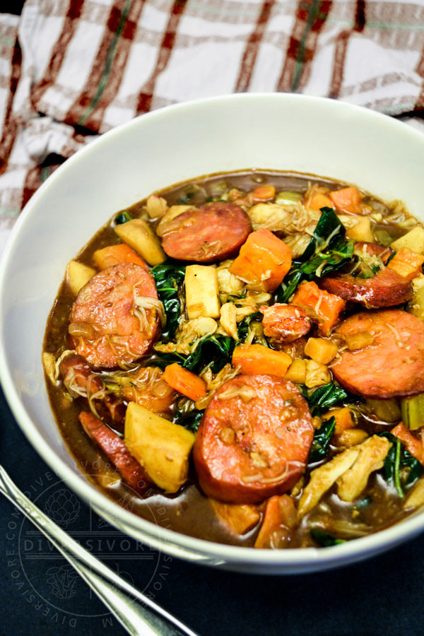 A bowl of winter gumbo made with Pacific Northwest ingredients, served beside a brown and white plaid towel and a spoon