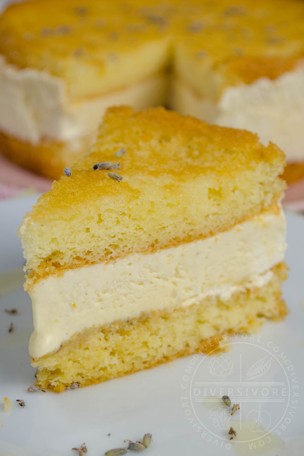 A slice of Lemon, Lavender, and Honey Semifreddo Cake on a white plate with the whole cake in the background