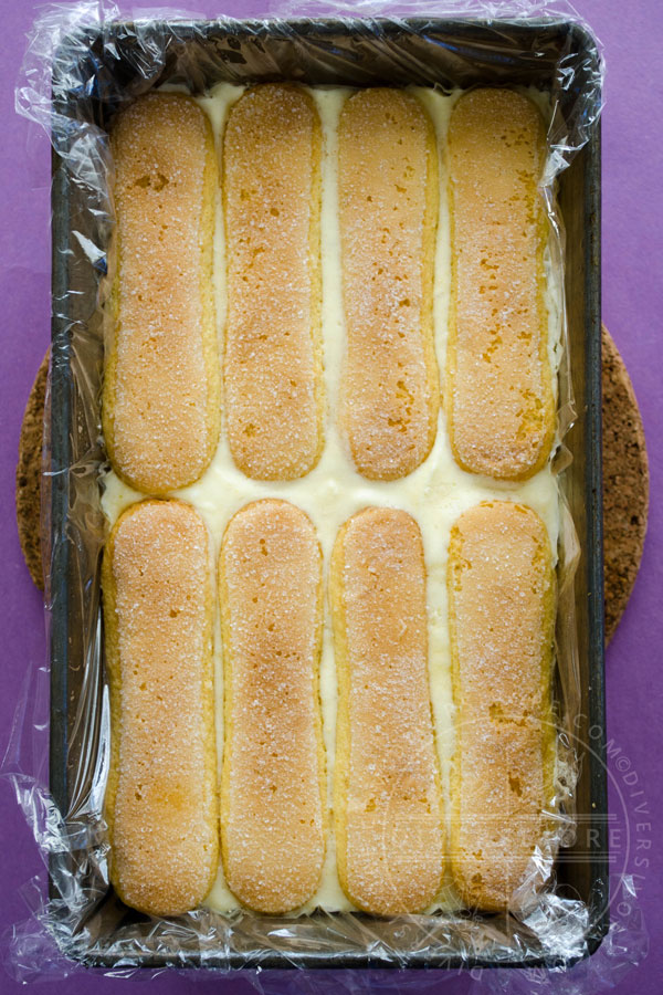 Lemon and lavender semifreddo shown in a baking pan with lady fingers, waiting to be frozen