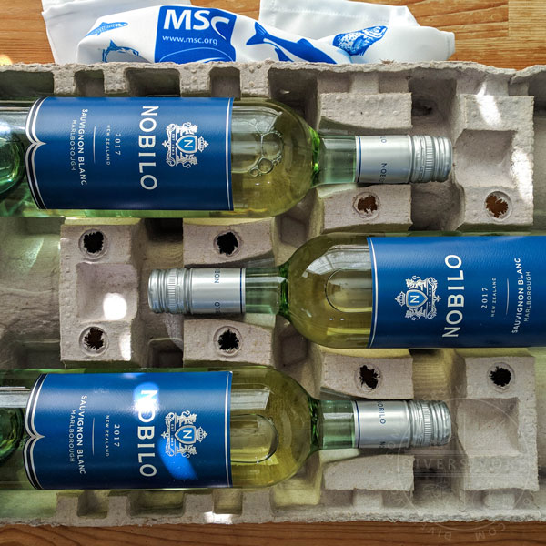 Three bottles of Nobilo Sauvignon Blanc in a packing case with a tea towel showing the Marine Stewardship Council logo