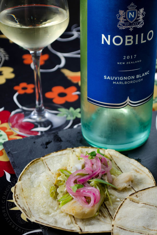 Pescado con vino - fish with white wine, cooked in a Mexican style, served in a taco on a slate board in front of a wine glass and Nobilo Sauvignon Blanc bottle