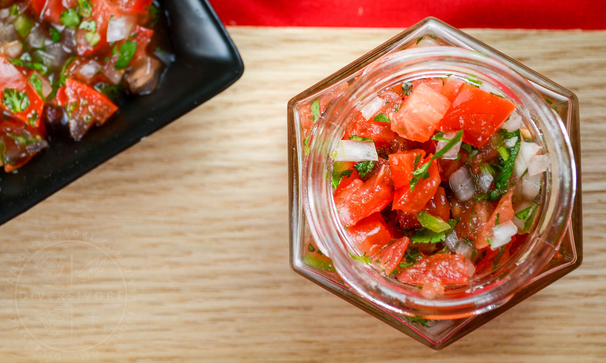 Pico de gallo salsa in a hexagonal jar on a wood surface