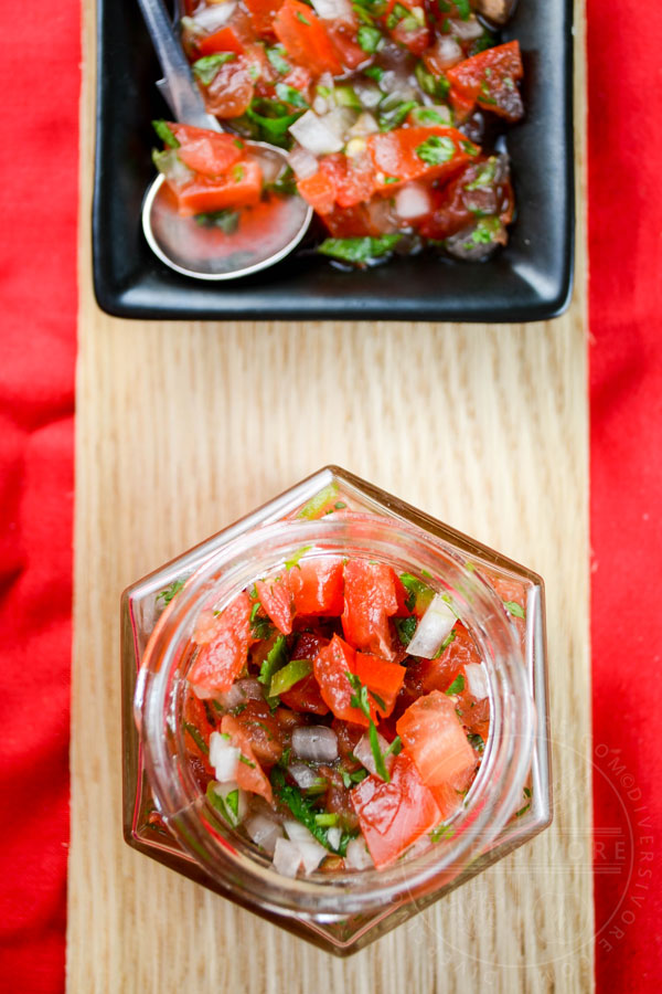 Pico de Gallo in a small hexagonal glass jar against a wood backdrop