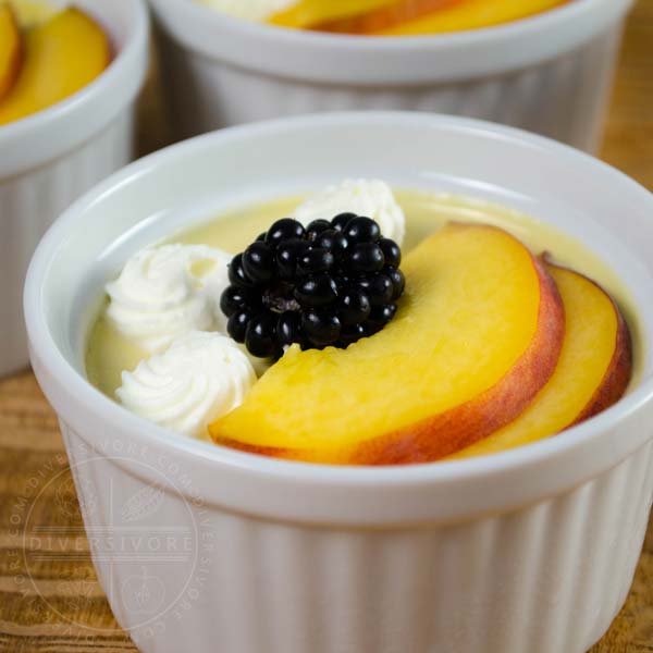Peach pots de creme with peach slices and a blackberry in a white ramekin, flanked by additional ramekins