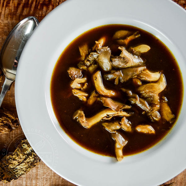 Smoky Mexican oyster mushroom soup in a white bowl with a spoon