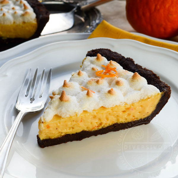 A slice of seville orange pie with meringue and a chocolate graham wafer crust, served on a white plate with a silver dessert fork