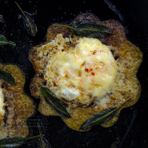 Squash Hole-in-One (aka Egg in a basket, aka Toad in the hole) made with eggs, acorn squash, aged cheddar, and fried sage, shown in a cast iron frying pan