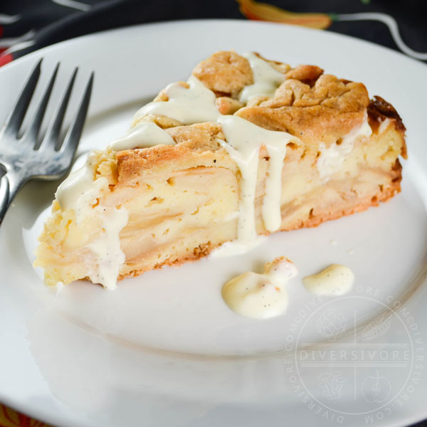 A slice of Swedish apple cake with vanilla sauce on a white plate with a silver fork