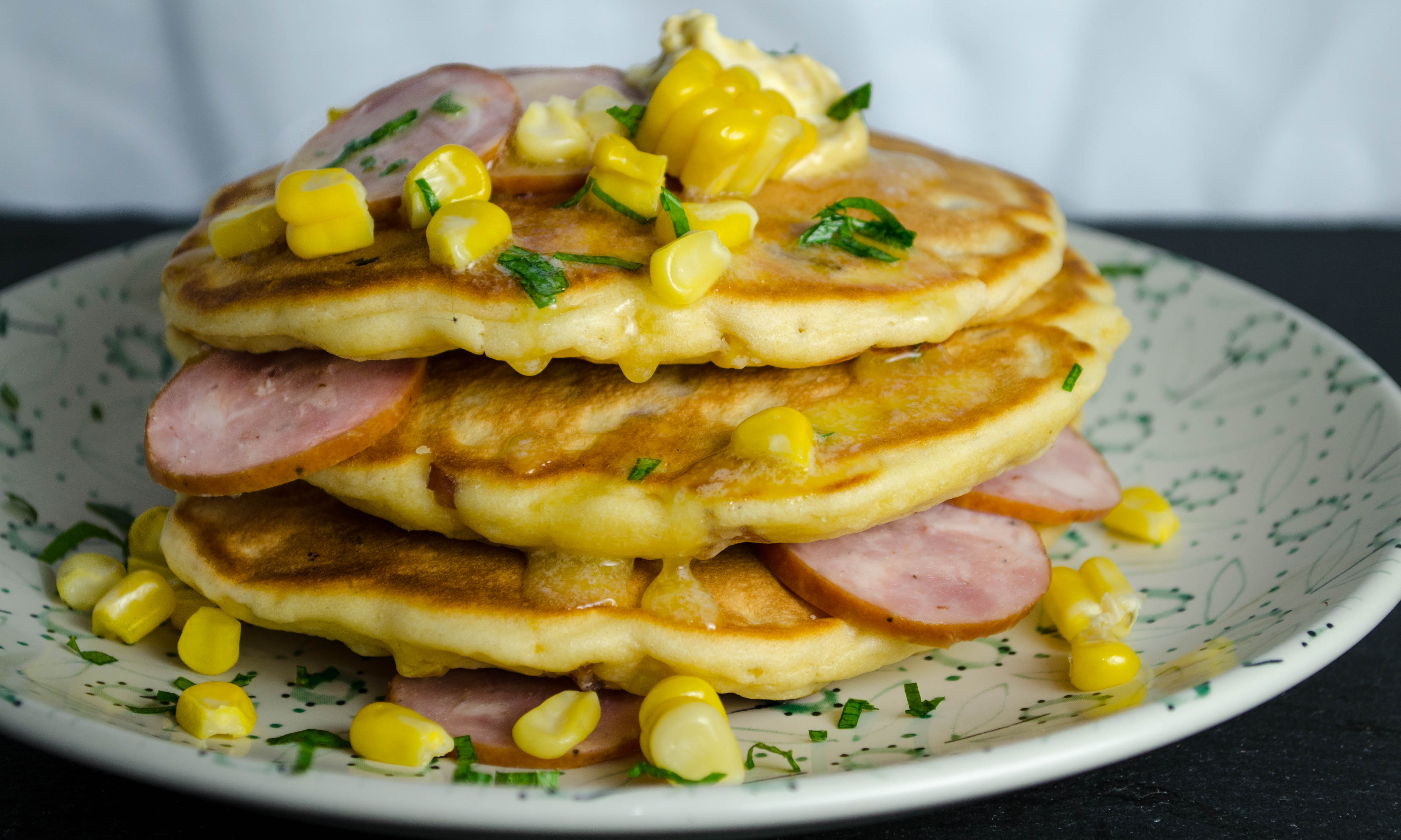 Savory pancakes with corn and kielbasa on floral patterned plate