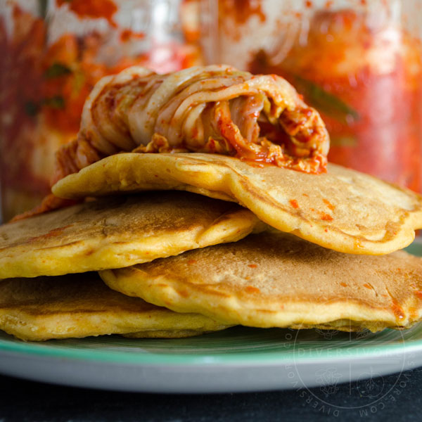 Kimchi and seafood pancakes on a green plate, topped with kimchi