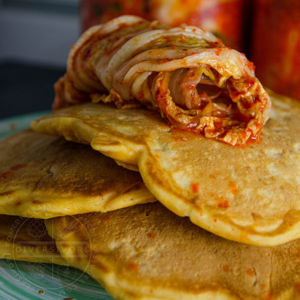 Kimchi and seafood pancakes on a green plate, topped with kimchi