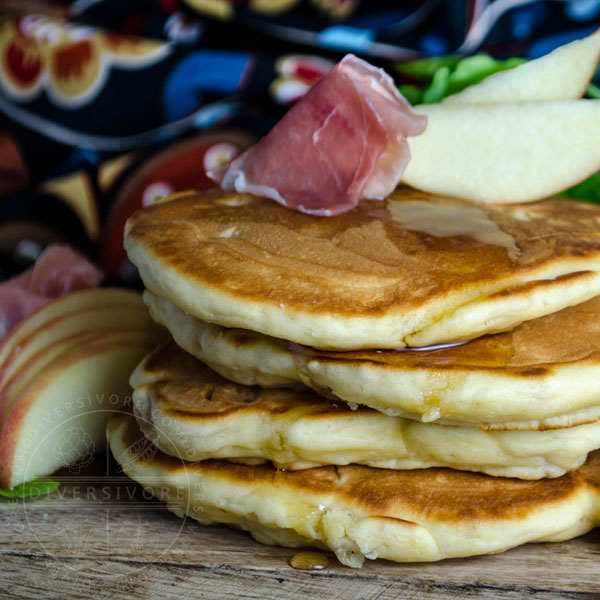 Prosciutto, apple, and arugula pancakes on a wooden board