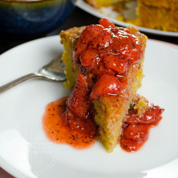 Strawberry polenta cake with strawberry and black pepper compote served on a white plate with a silver fork