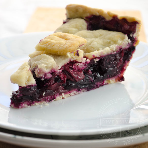 A slice of cherry-blueberry pie on a white plate