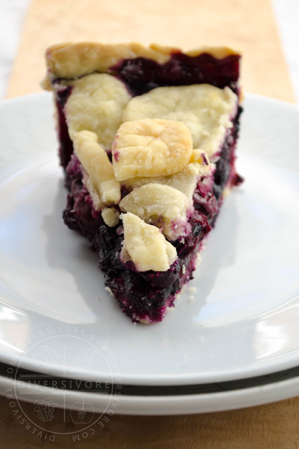 A slice of cherry-blueberry pie on a white plate