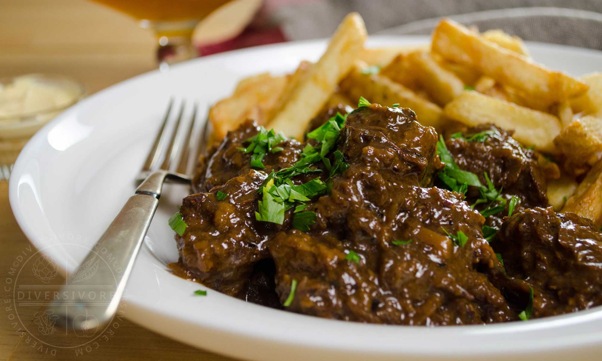 Carbonnade - Flemish Beef and Beer Stew in a white bowl with fries and a silver fork