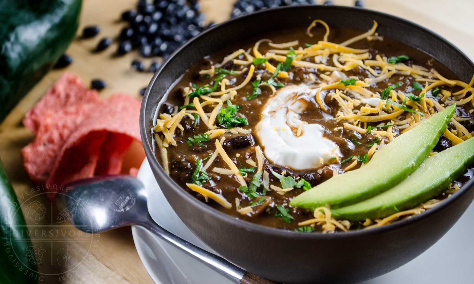 A bowl of Chili Mole with avocado, sour cream, and shredded cheese