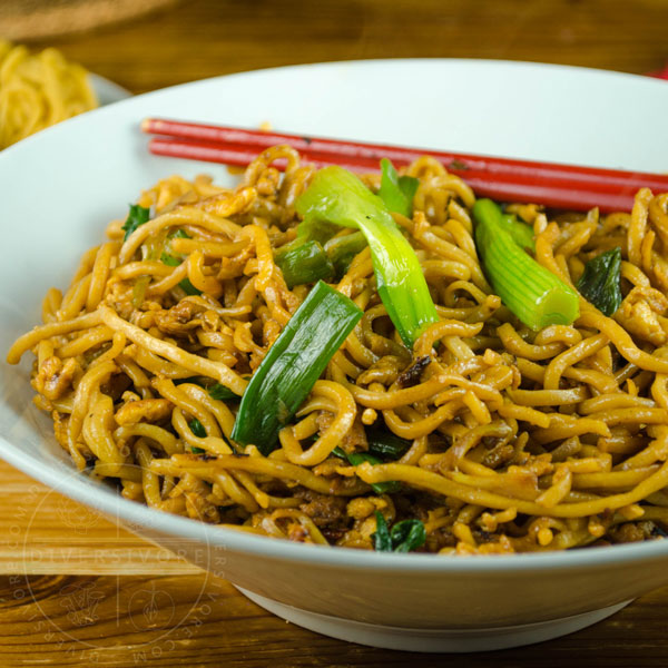 Soy sauce fried noodles in a white bowl with red chopsticks