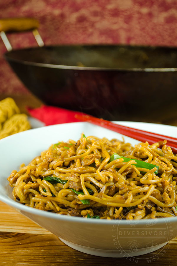 Soy sauce fried noodles in a white bowl with red chopsticks