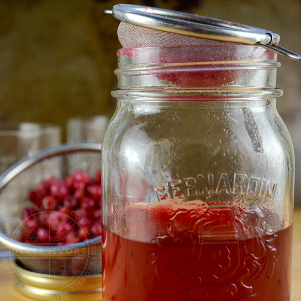 Red currant gin in a mason jar, topped with a strainer