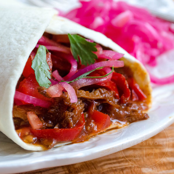 Carne Entomatada in a tortilla shell with pickled red onions