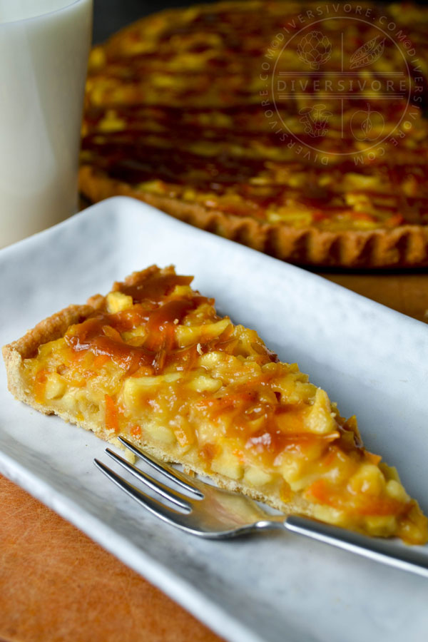 A slice of kumquat apple tart with whiskey caramel on a rectangular plate with a small dessert fork