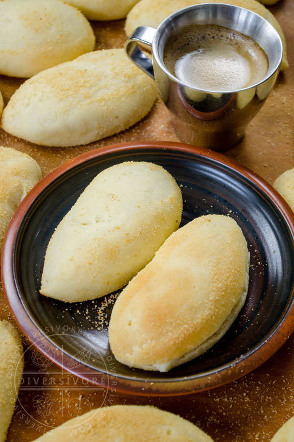 Pandesal on a dark plate with a cup of coffee