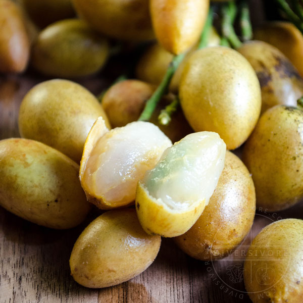 Wampee fruit, shown with the skin on and peeled