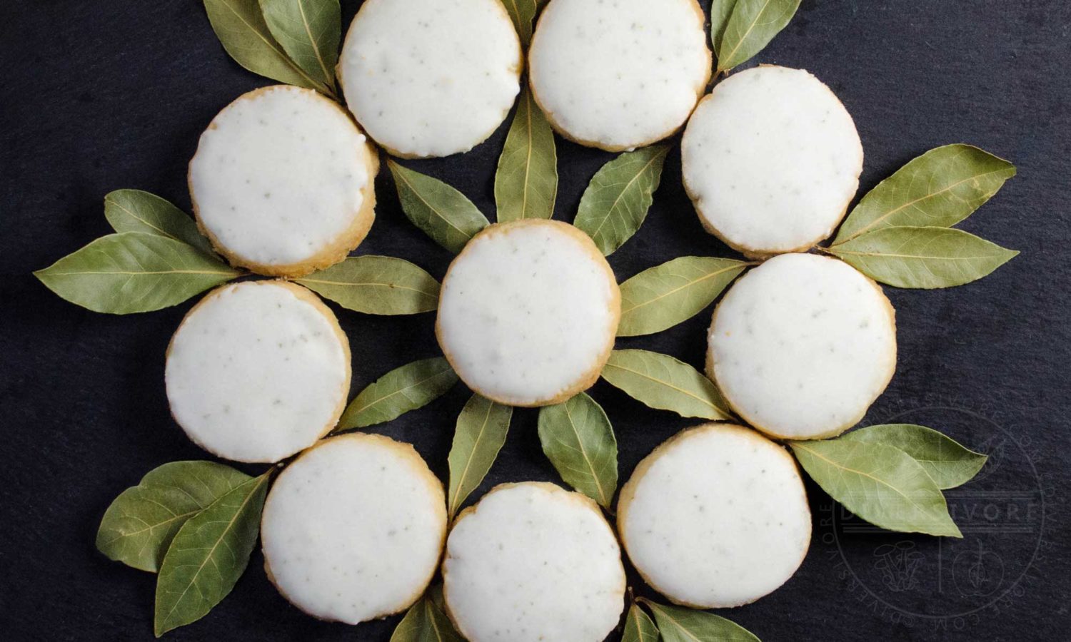 Bayleaf and lemon shortbread arranged in a decorative wreath-like circle, surrounded by bay leaves